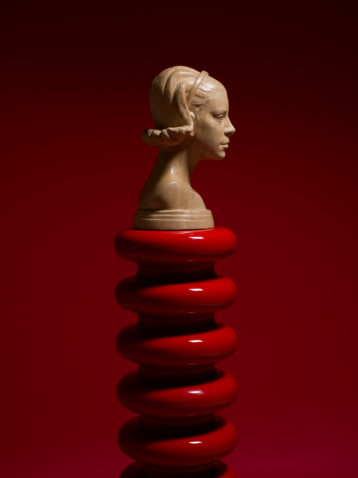Bust of a woman on a red spiral stand against a red background