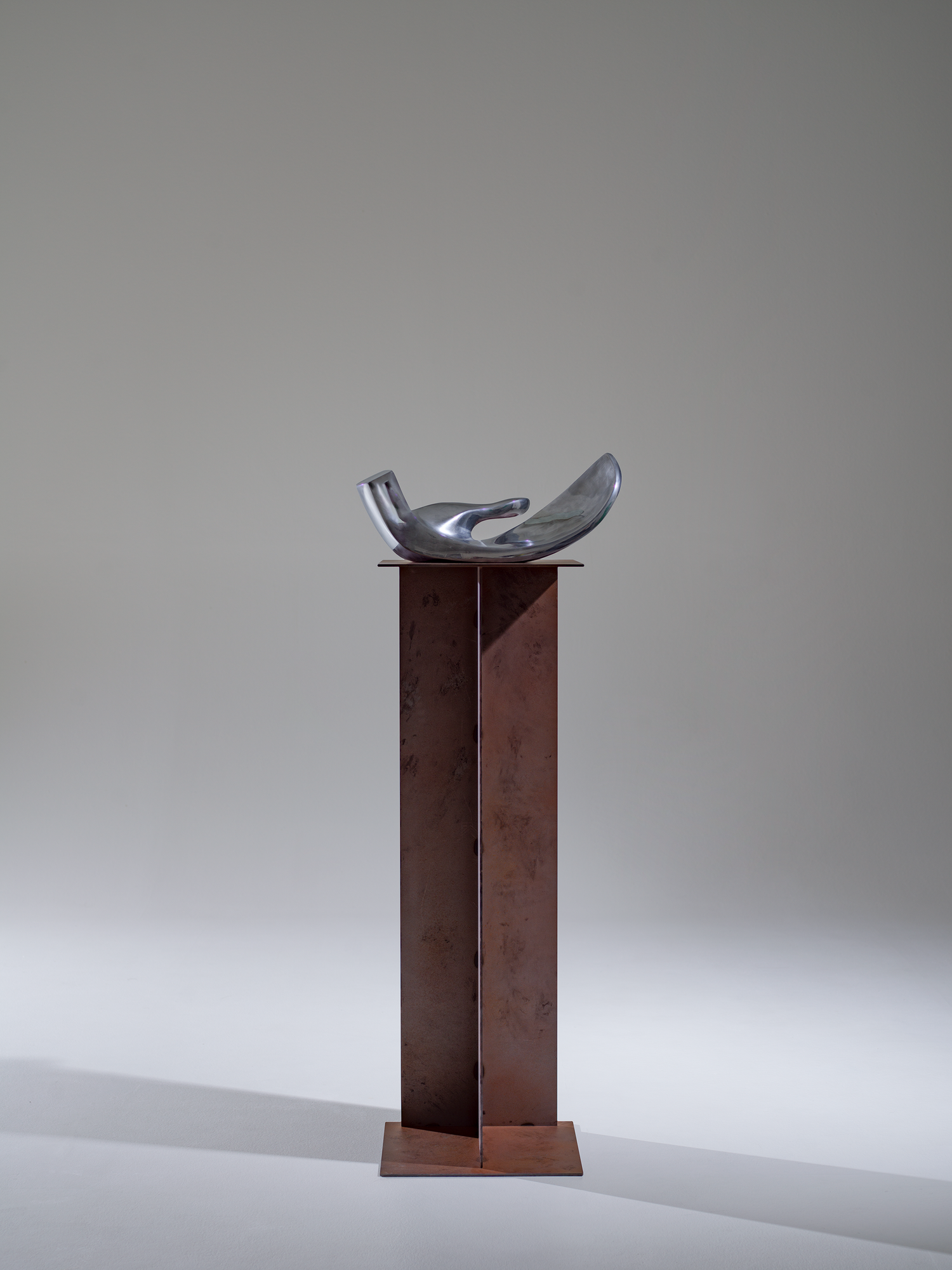 Metal sculpture on a pedestal against a plain background