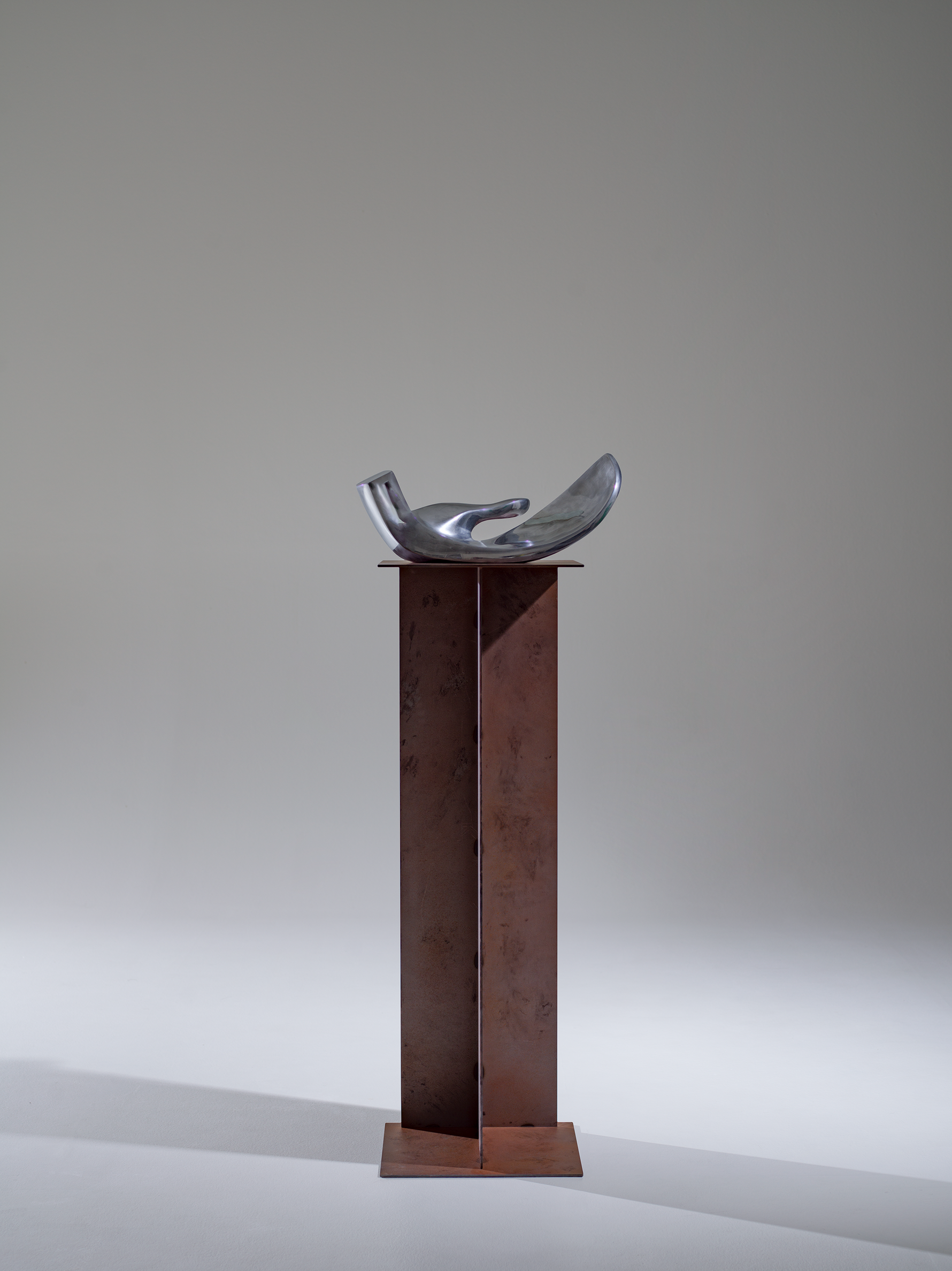 Metal sculpture on a pedestal against a plain background